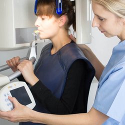 Einfühlsame Zahnmedizinische Angestellte beim Röntgen einer Patienten